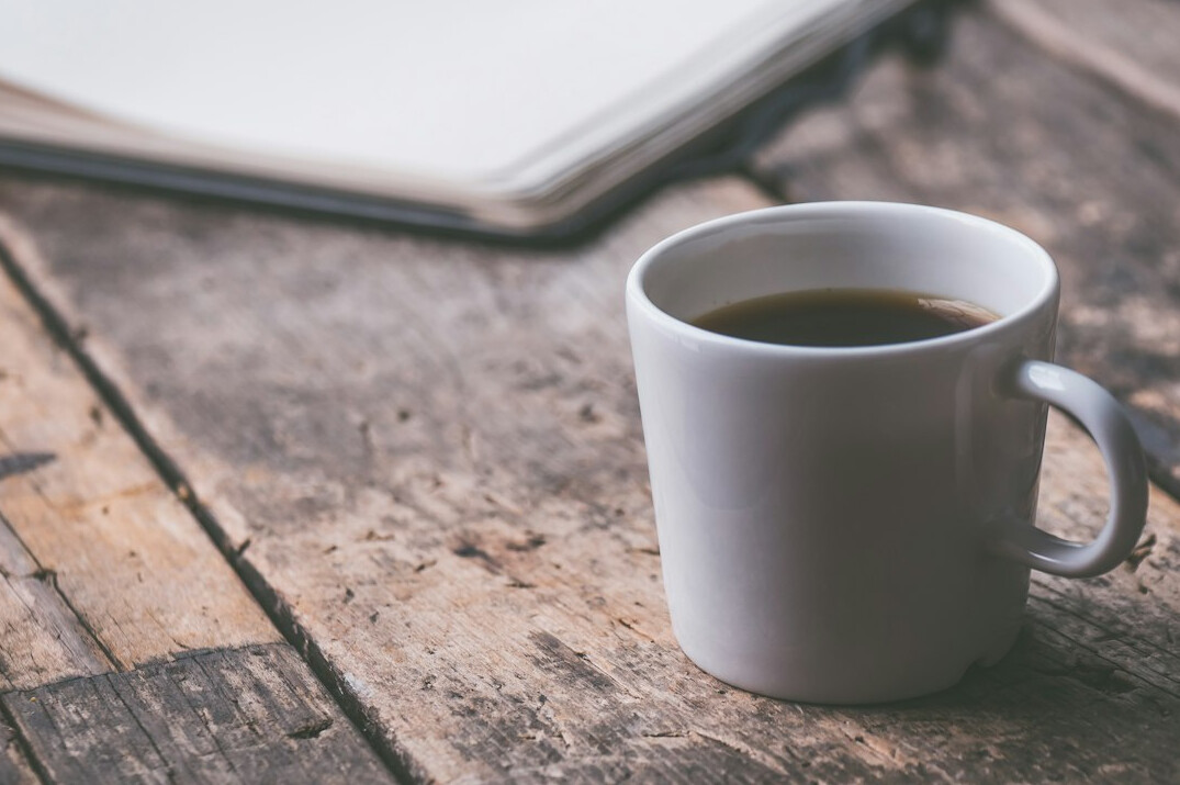 Open notebook and laptop on a desk with coffee, representing writing and research